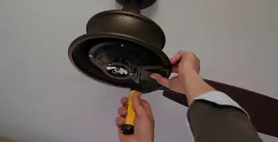 Electrician installing ceiling fan mounting bracket and fixture in Albany, NY