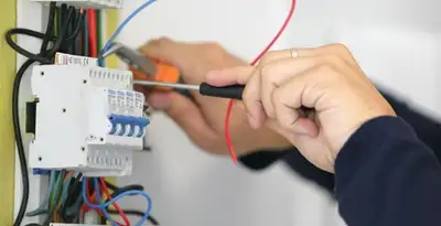 Electrician installing and adjusting circuit breakers in an electrical panel in Albany, NY