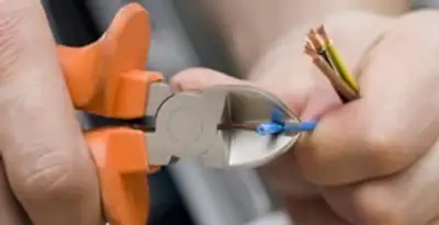 licensed electrician performing precise wire cutting and preparation during electrical service in Albany, NY