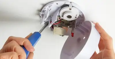 Certified technician wiring smoke detector during installation in Albany, NY